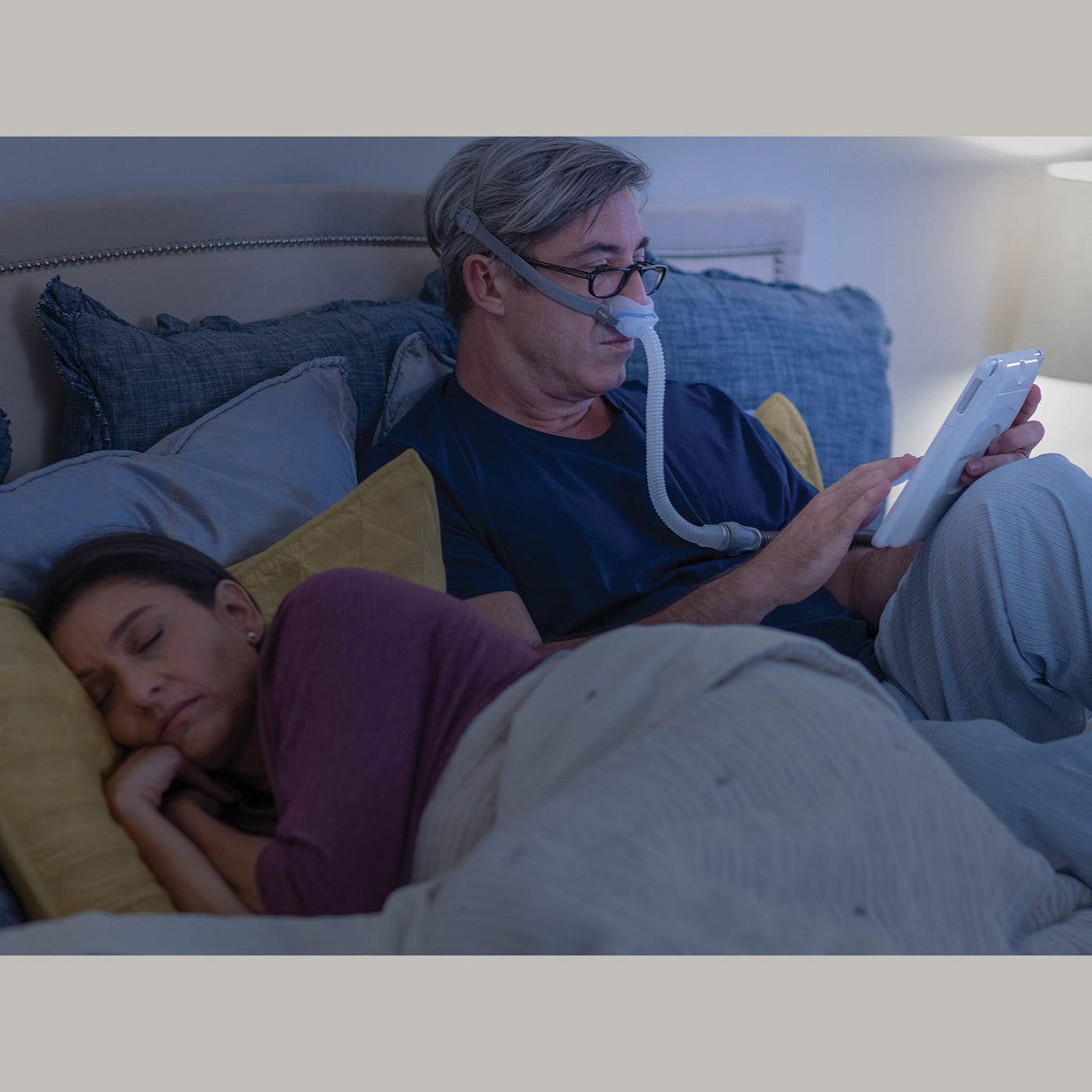A man reading in bed using a cpap airfit n30 mask